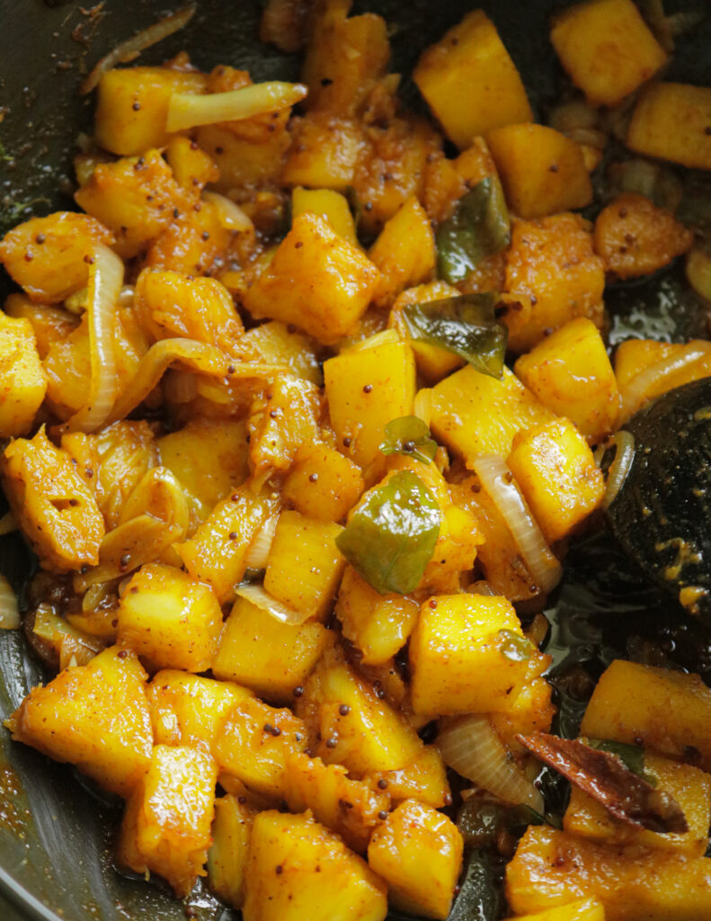 cubed pineapple cooking in a frying pan.