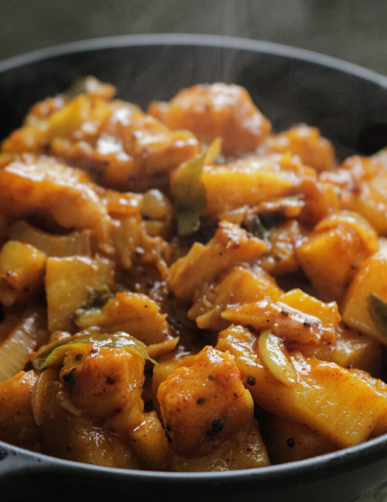 cubed pineapple cooked as a spicy pineapple curry with onions and curry leaves.