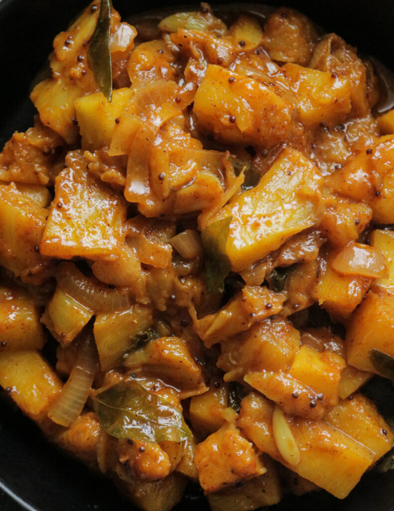 pineapple with curry powder and sliced onion and garlic served in a bowl.