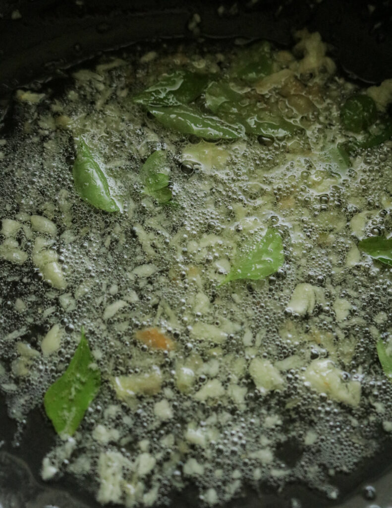 curry leaves and garlic tempered in oil to cook the squid curry.