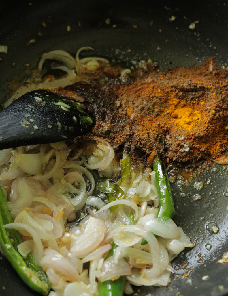 adding the spice powders to the cooked onions, green chillies and curry leaves.