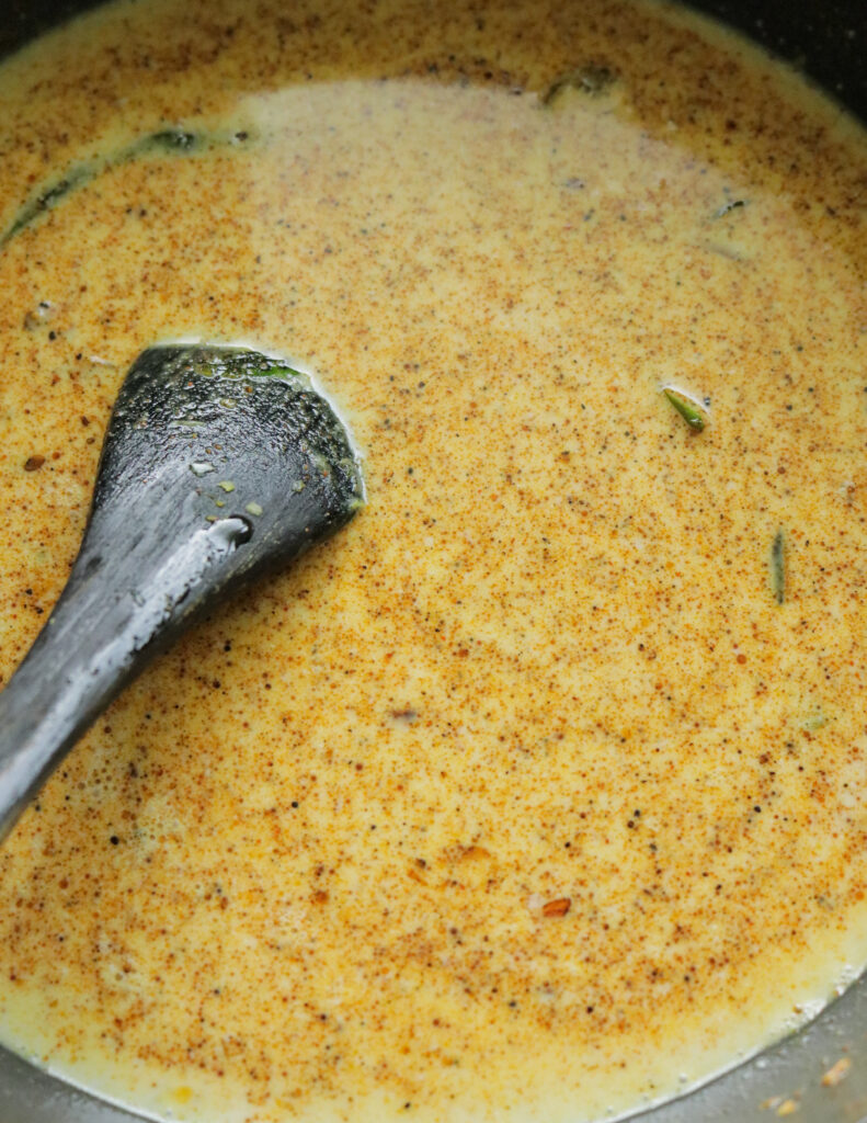 adding coconut milk to make the gravy for the calamari curry.