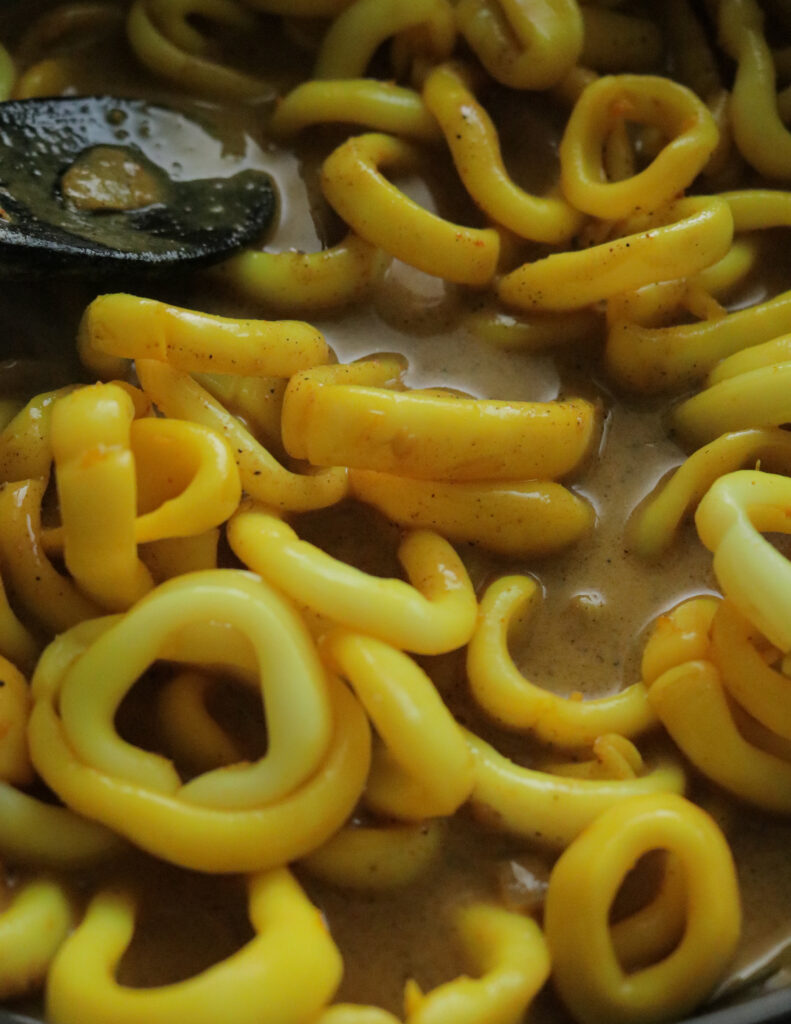 adding the boiled calamari ring to the coconut milk gravy.