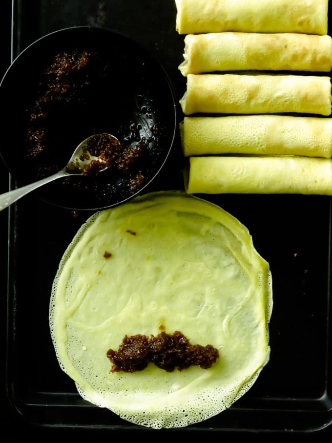 How to roll the coconut milk pancakes with the jaggery-coconut filling in them.