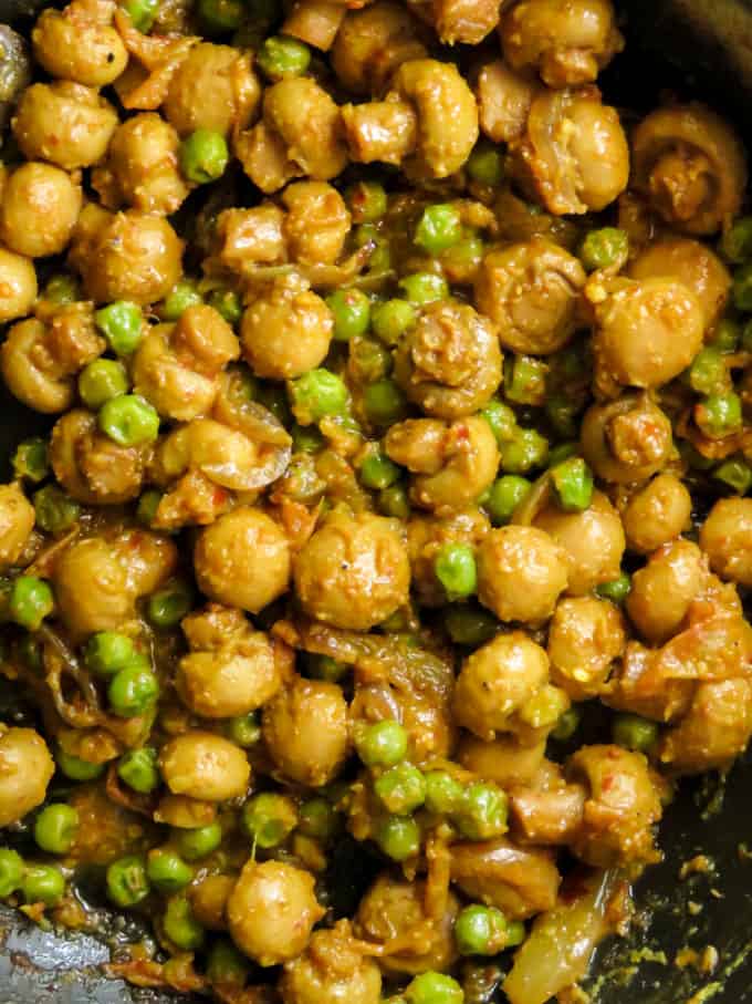 Indian mushroom and green peas masala curry cooked in a wok.