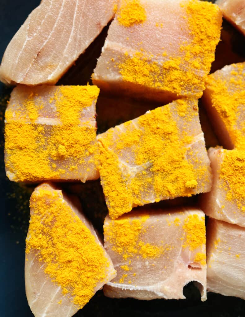 chunks of sailfish with turmeric to rinse and wash