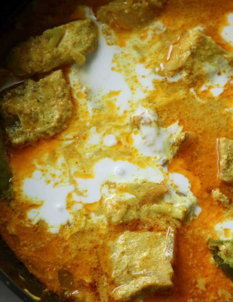 adding coconut milk to the cooked chunks of fish cubes.