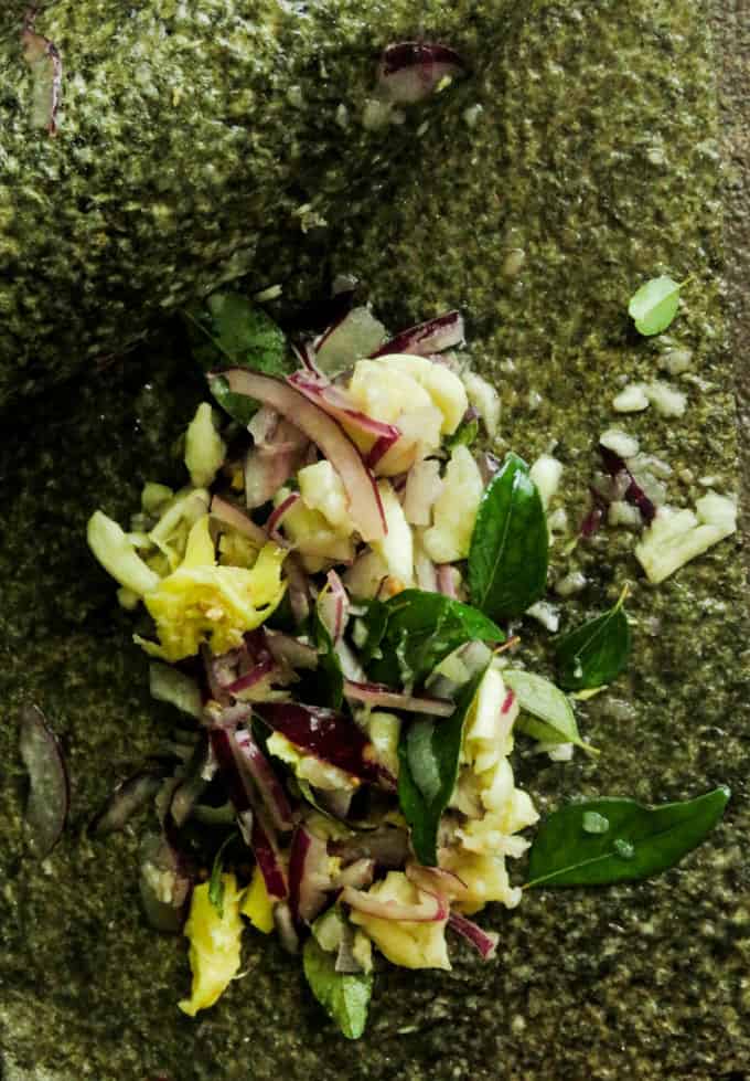 grinding rasam ingredients on a grinding stone.