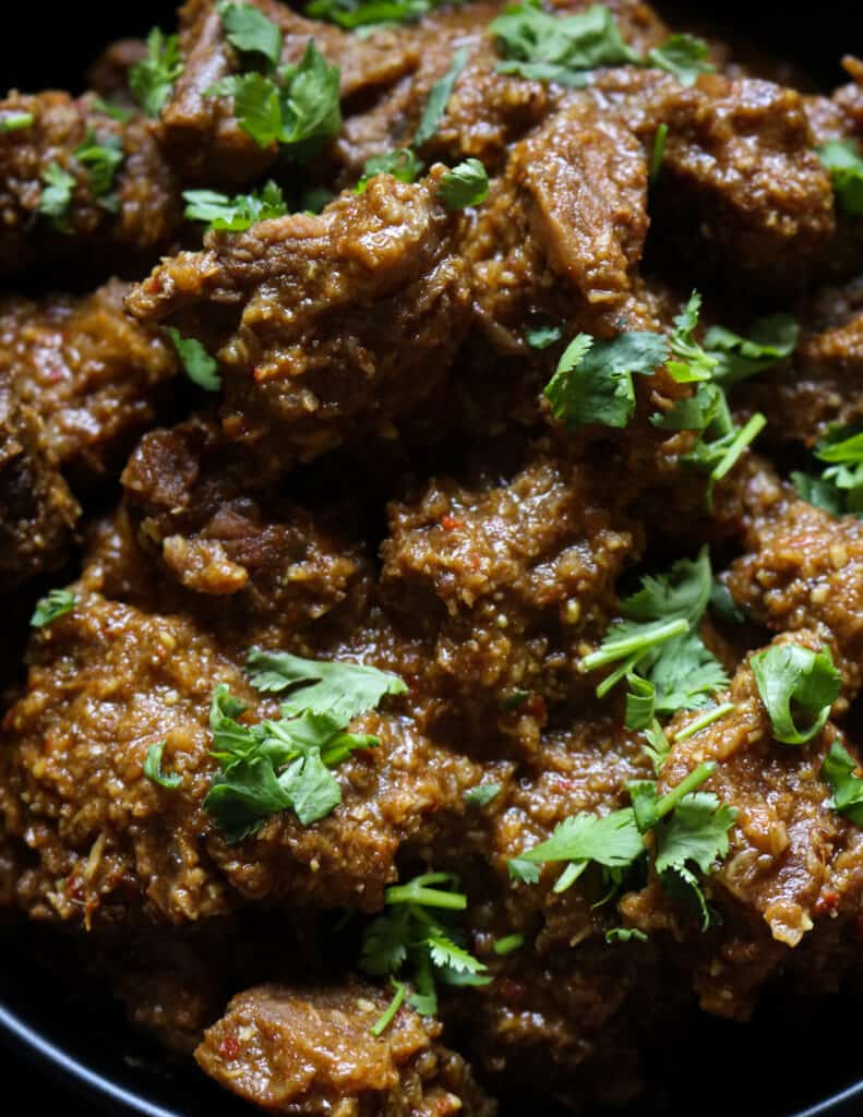 beef korma placed in a bowl with chopped coriander garnishing the beef curry.