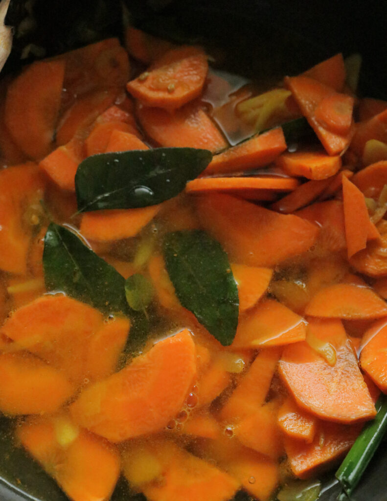adding water to cook the carrot curry.