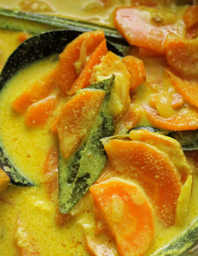 slices of carrot cooked in coconut milk wit curry leaves and mixed with a woooden spoon