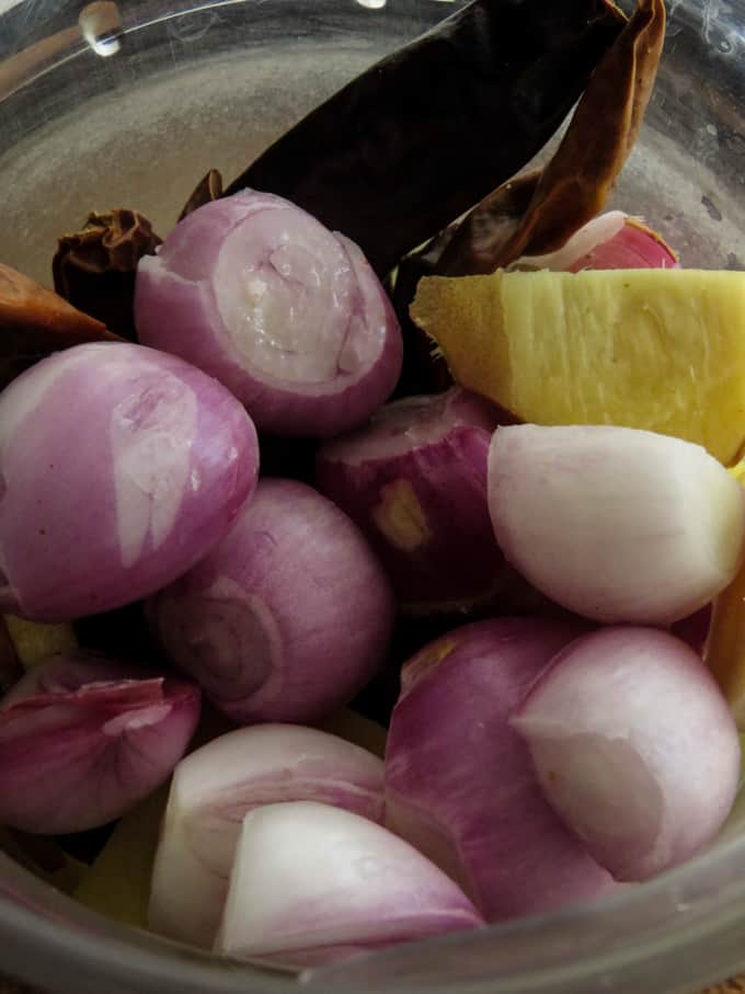 Adding the shallots, ginger, galangal, lemongrass,  garlic, turmeric to a blender to make the rendang paste.