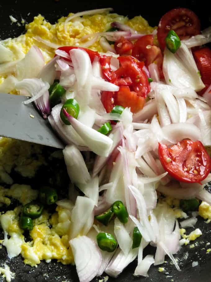 mixing onions to the scrambled eggs to make the chicken kottu.