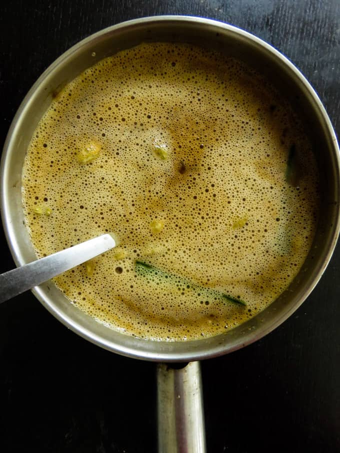 Adding the egg mixture to the jaggery syrup.