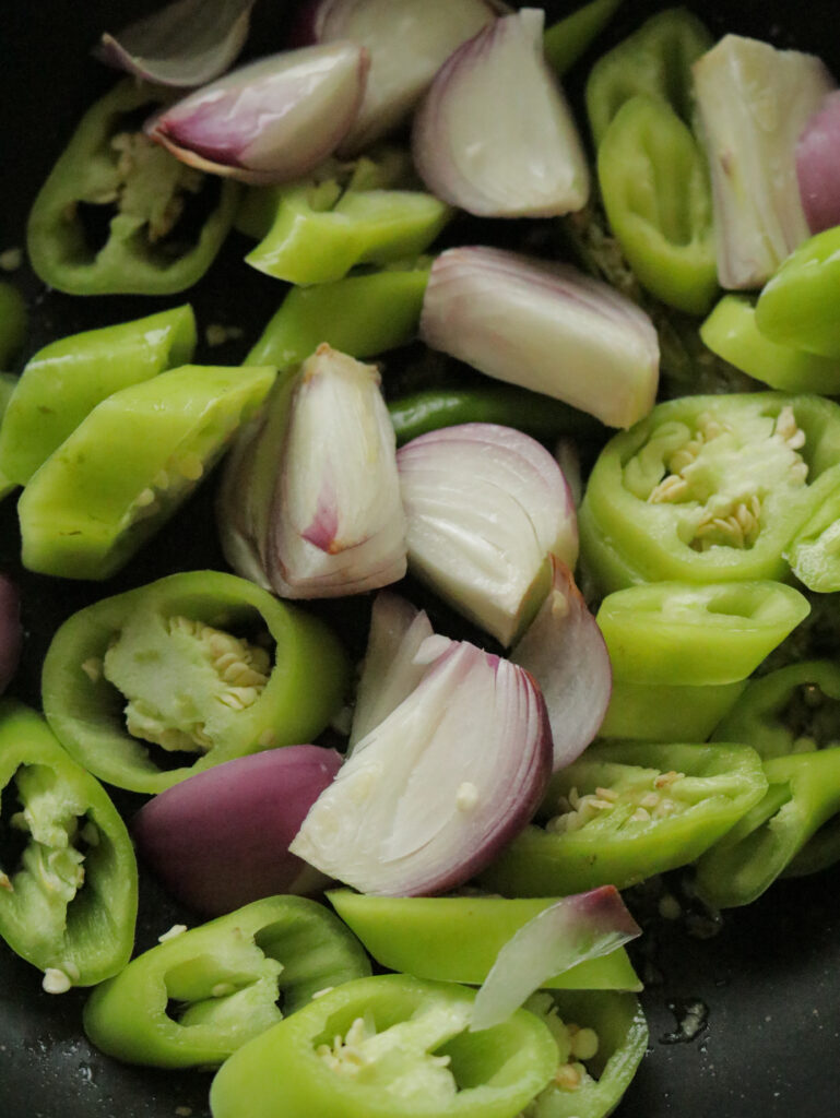 adding the onion wedges and green peppers to the minced ginger garlic in oil