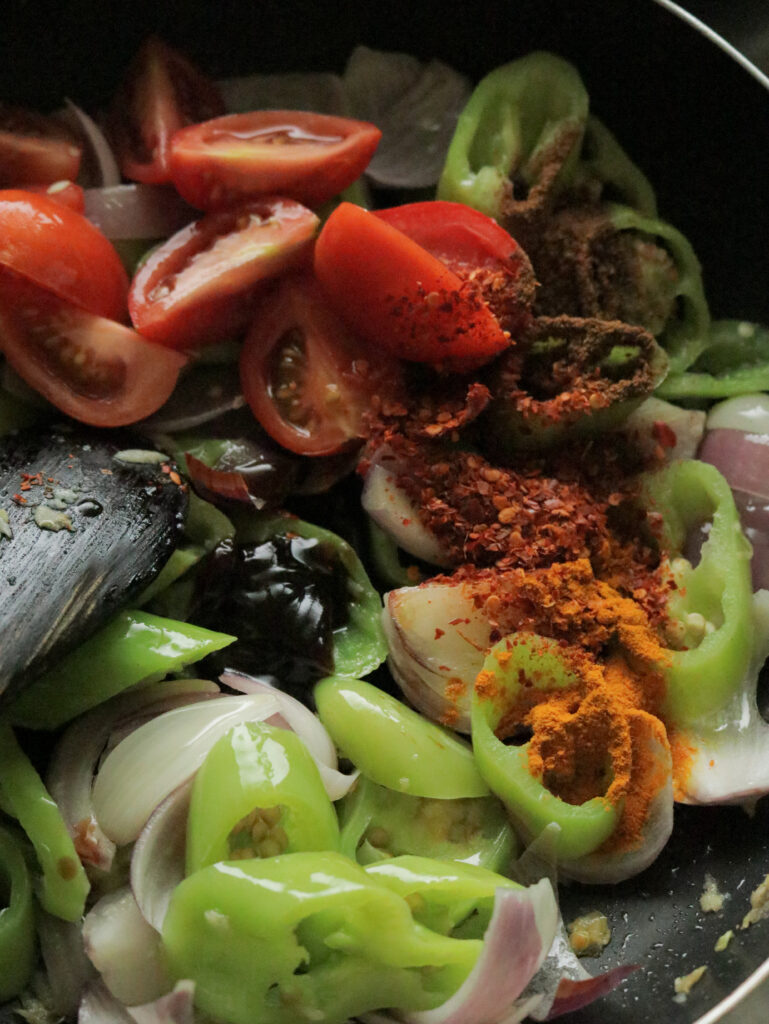 cooking the wedges of onions, green peppers, tomato, red chillies in oil