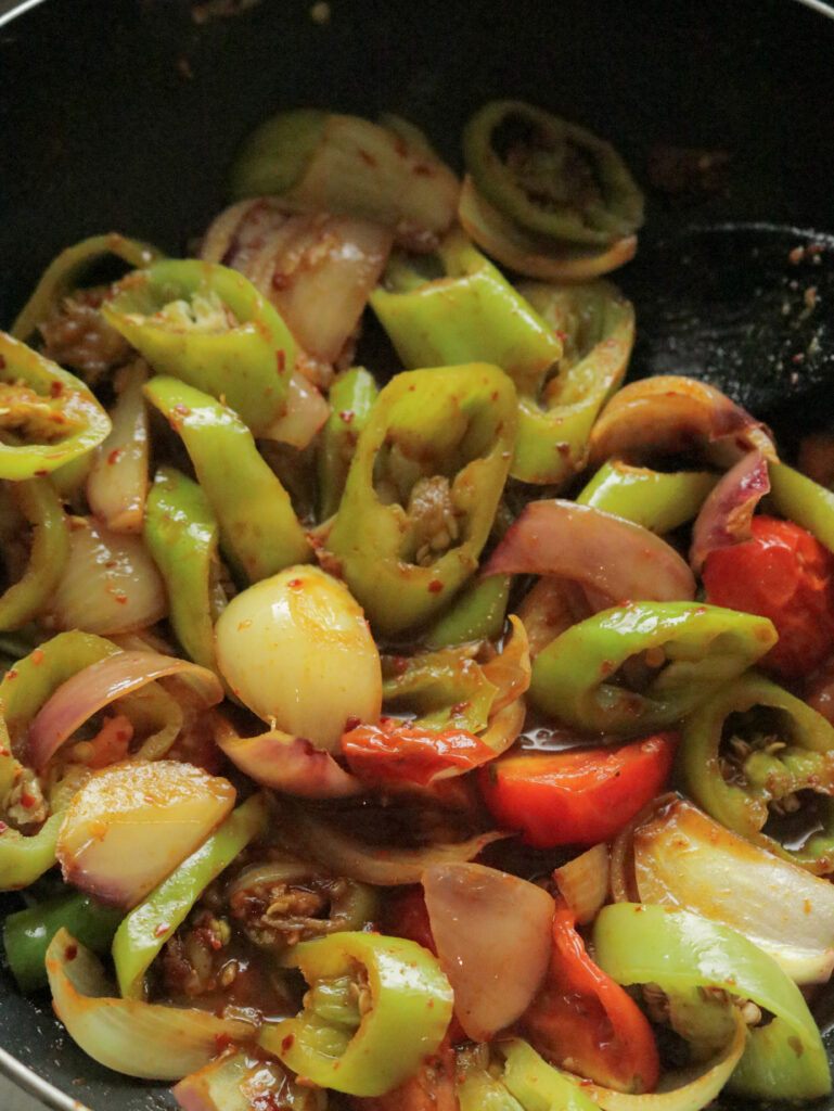 cooked ingredients wedges of green peppers, onions and tomatoes  to make devilled sausages