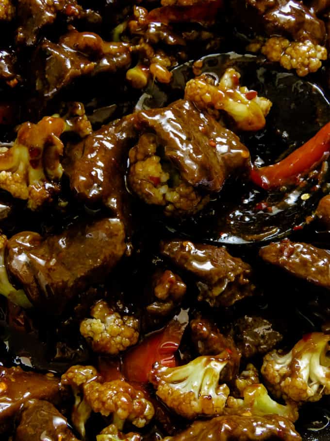 close up of a wooden spoon holding pieces of beef teriyaki.