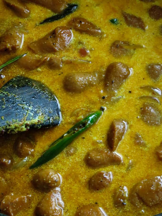 adding coconut milk to the sausage curry.