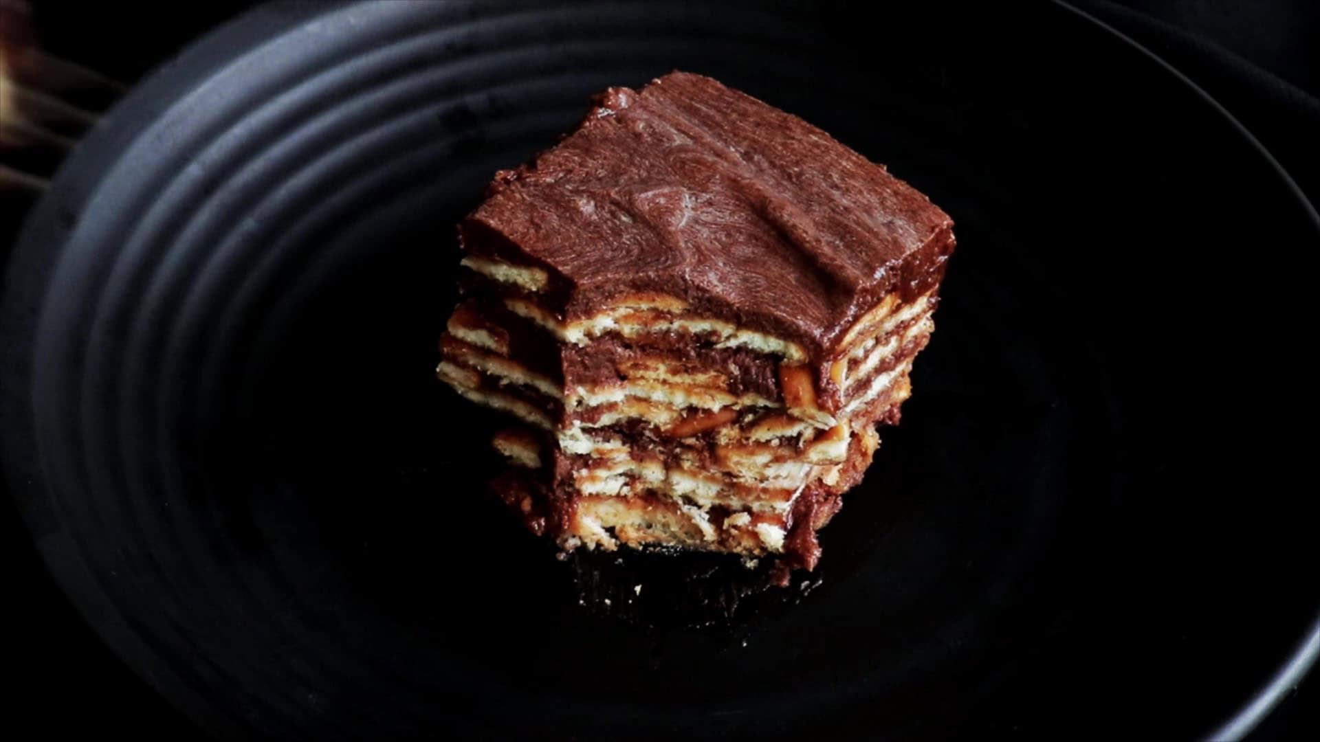 layers of biscuit and chocolate makes the chocolate biscuit pudding served in a black plate.