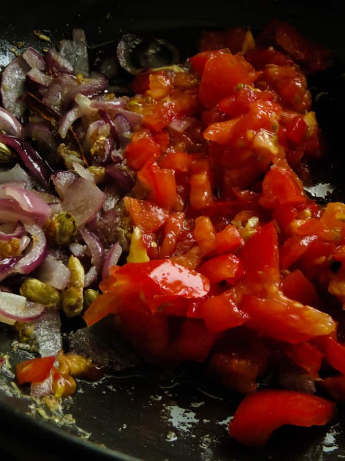 add the chopped tomatoes to the frying onions to make the chicken pasanda.