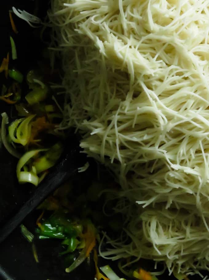 adding the cooked noodles to the cooked vegetables.