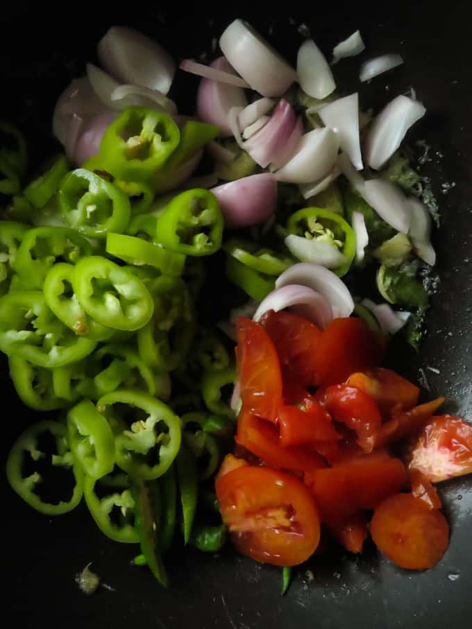 adding all the onions, tomatoes to cook in a wok.