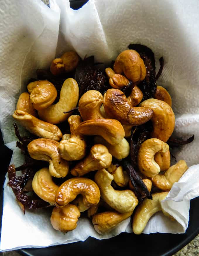 fried cashews and onions in a platter, over paper towels to absorb extra oil.