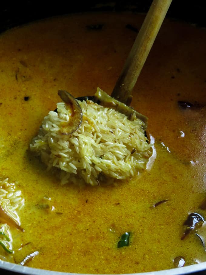 adding water and basmati rice to the masala mix to make the biryani.