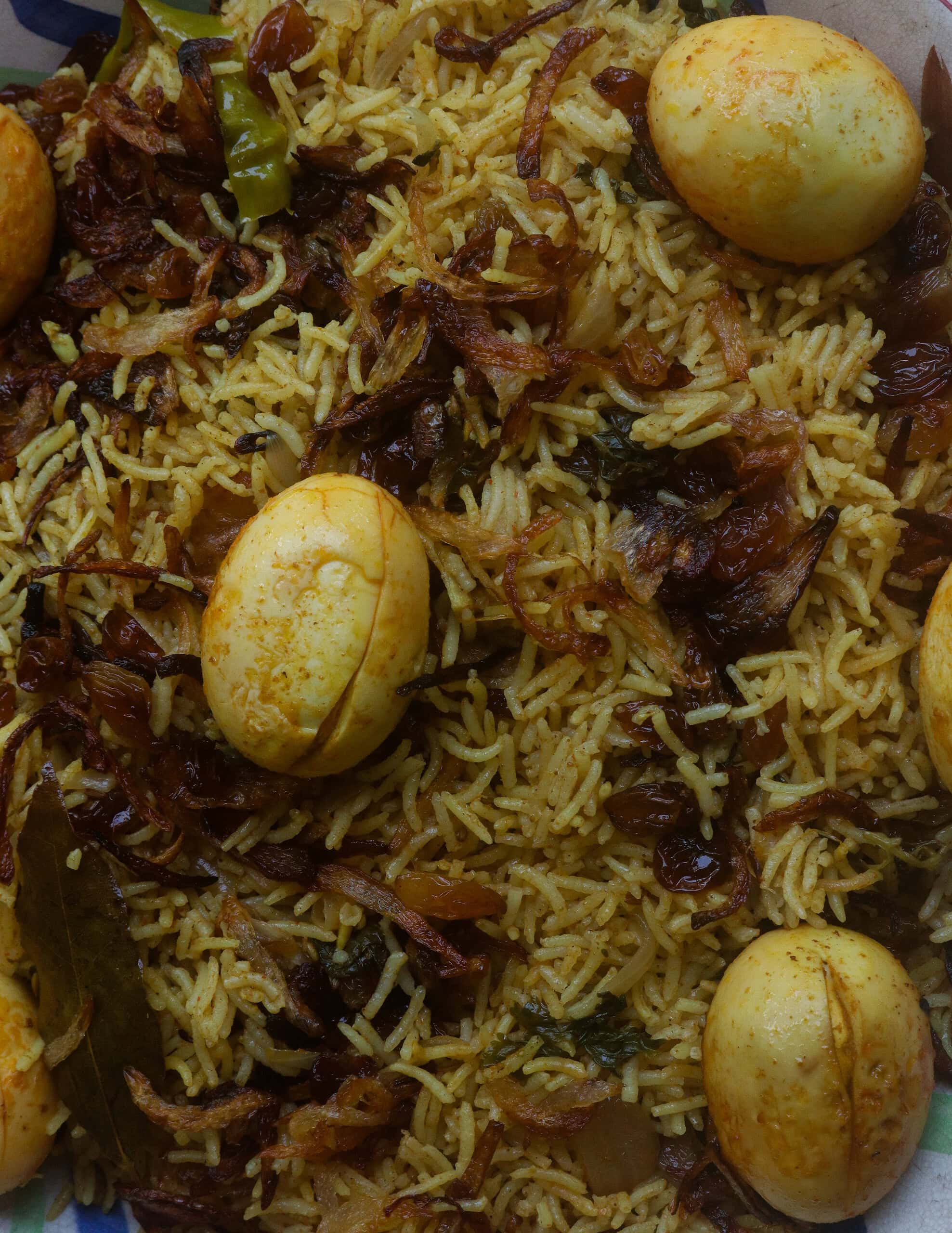 egg biryani, with mixed fried onions, raisins and eggs on top of the rice.