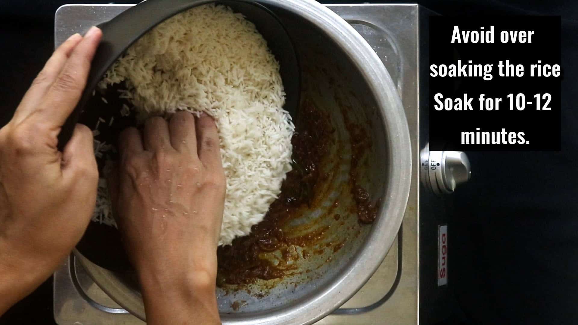 adding the soaked rice to the masala paste to cook the egg biryani.