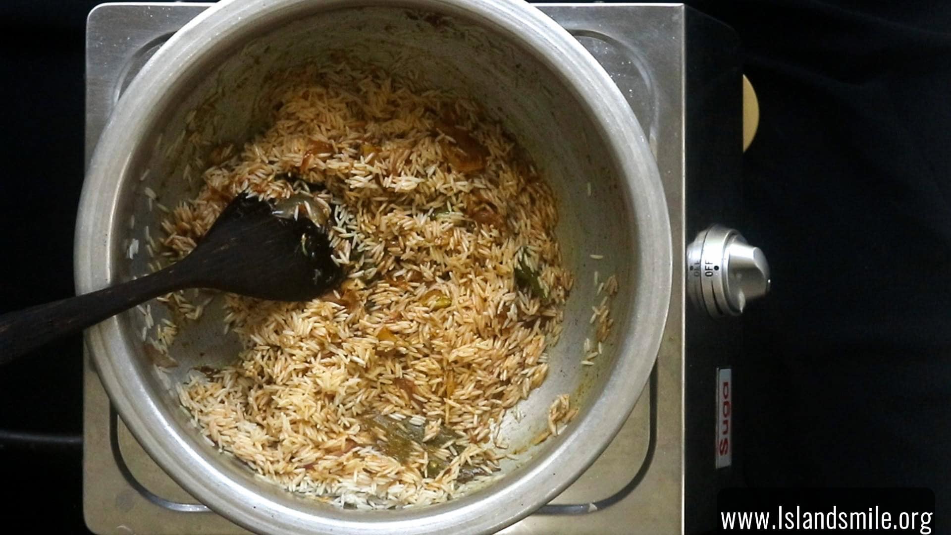 cooking the rice in the masala paste to make the egg biryani.