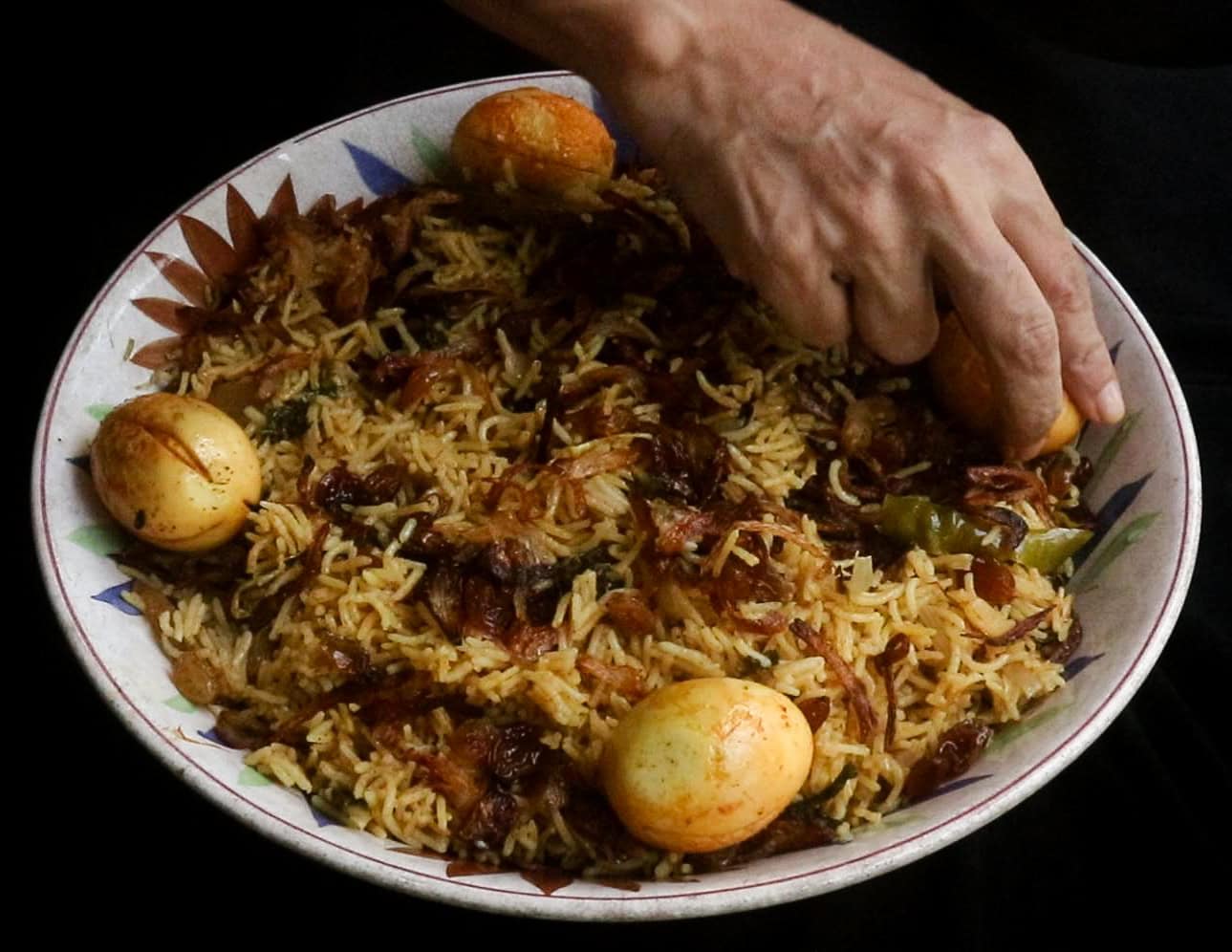 a platter of egg biryani full of fragrant basmati rice and garnishes.