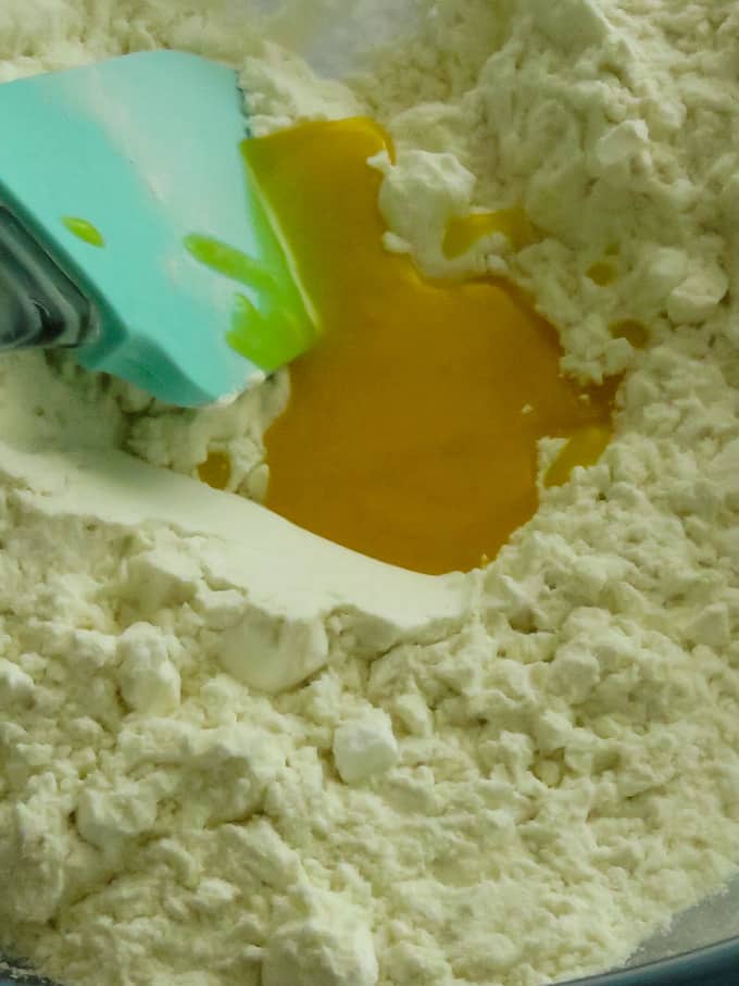 adding the ghee to the flour mixture to make the nankhatai.