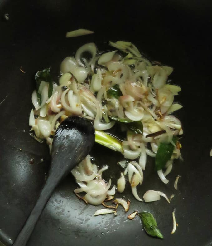 cooking onions, garlic and curry leaves to make vegetable fried rice.