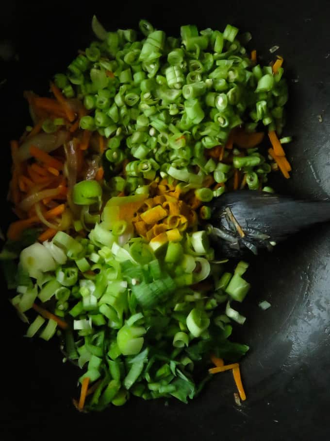 adding chopped beans and leaks to make the vegetable mixture for the fried rice.