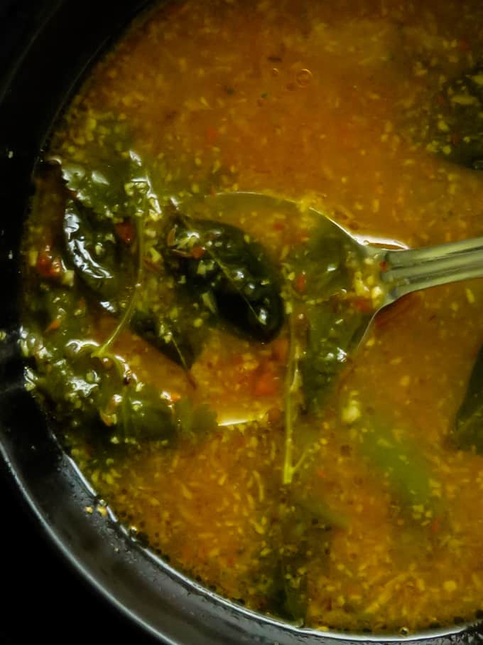 tomato rasam bowl with a spoon in the bowl