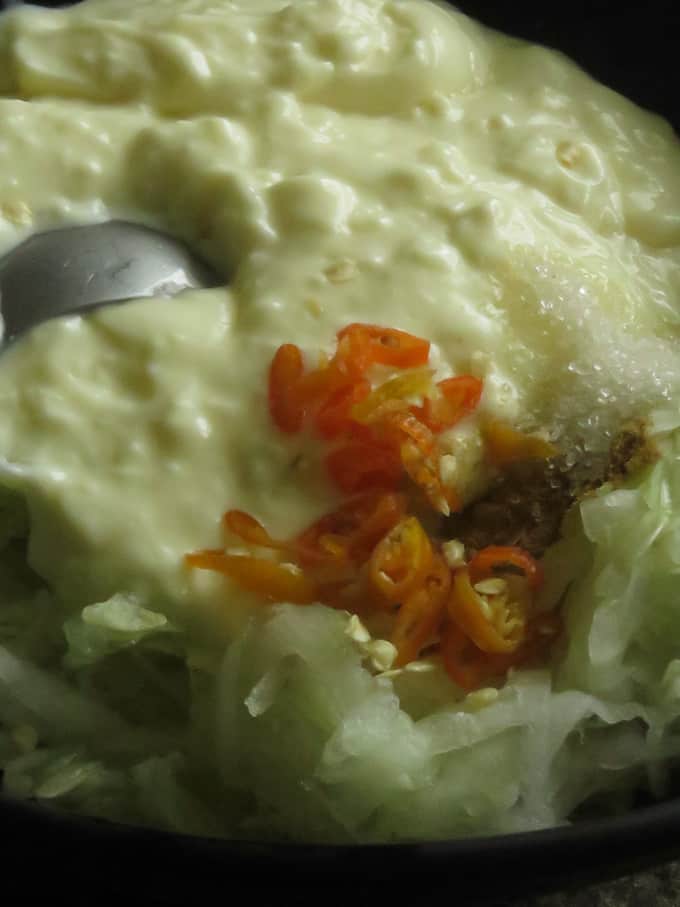 mixing grated cucumber, yogurt with cumin powder, chillies, seasoning and sugar to make the raita.