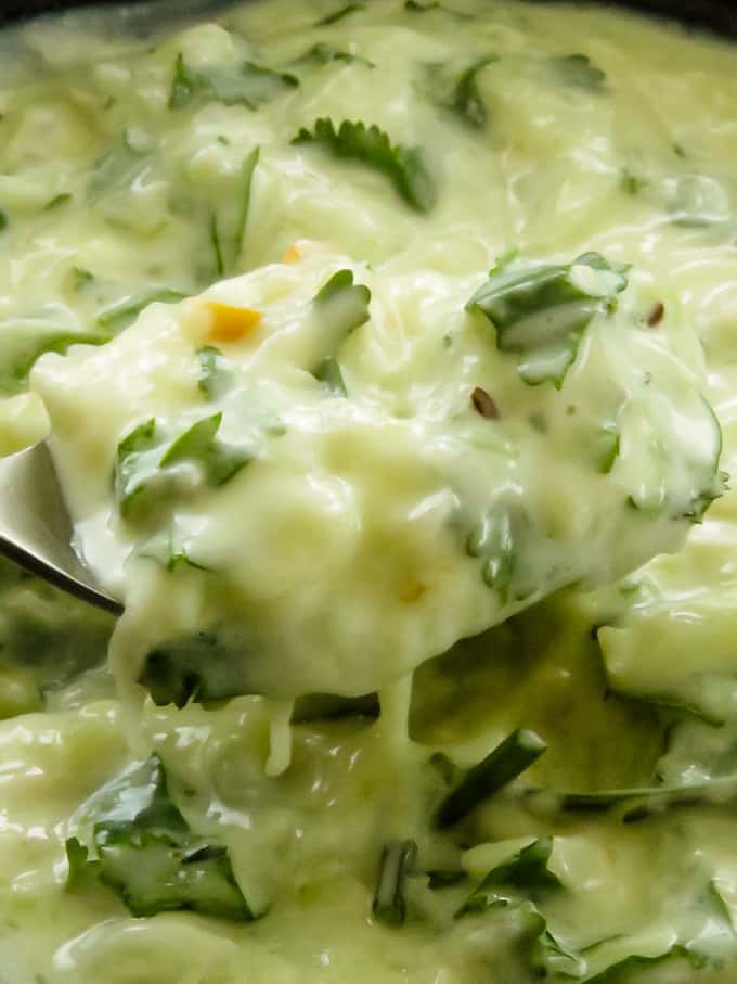 cucumber raita scooped from a spoon.