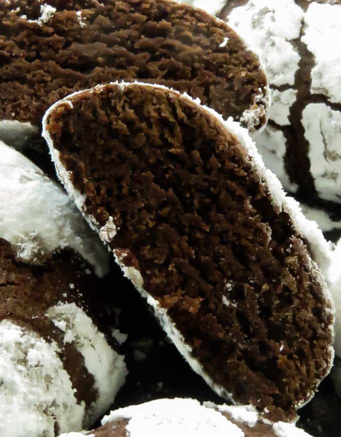chocolate crinkle cookies are broken into two showing the intense chocolatey inside of the crinkle cookies.
