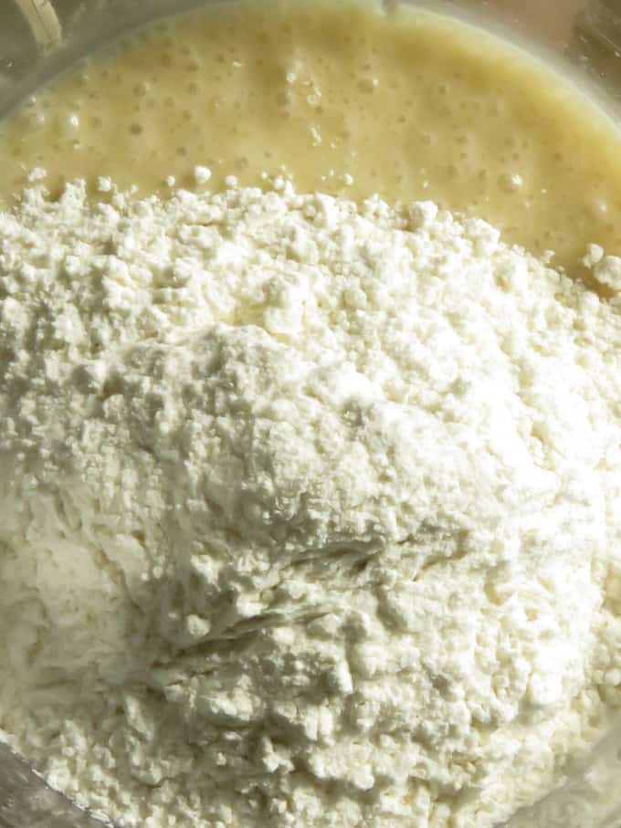 adding flour to the blended banana to make the banana pancakes.