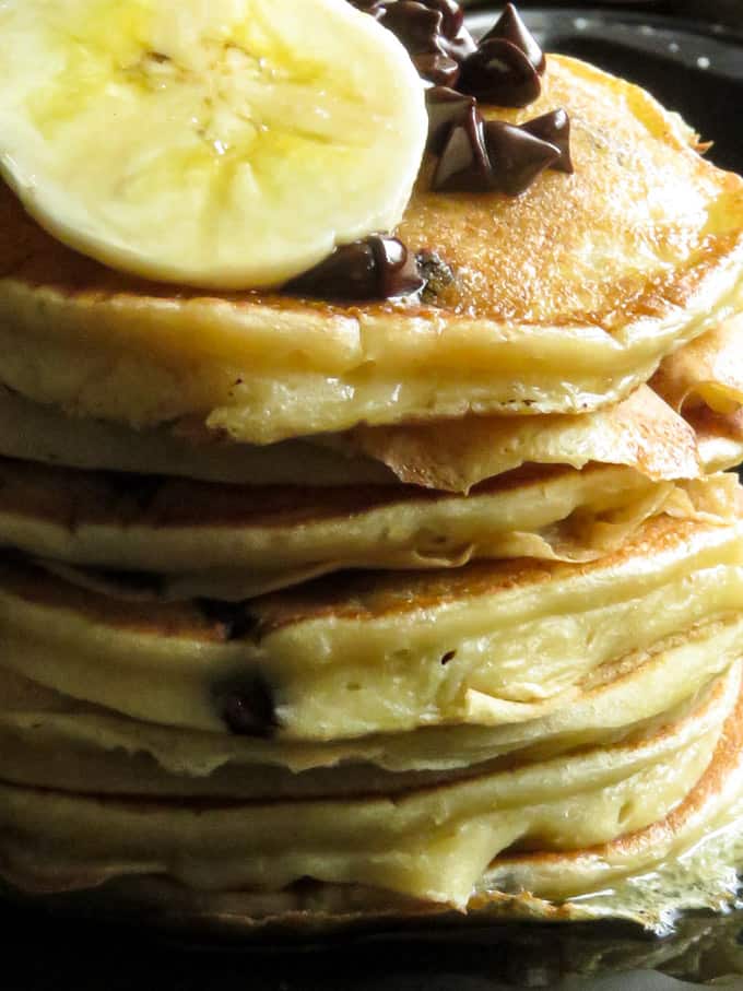 Fluffy banana pancakes with slices of banana and extra chocolate chips.