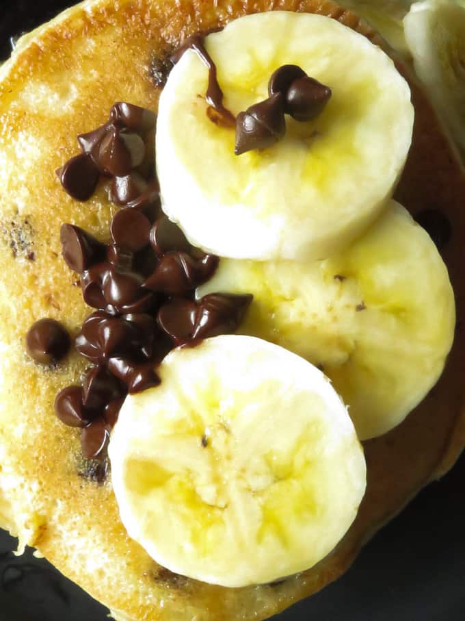 Fluffy banana pancakes with slices of banana and extra chocolate chips.