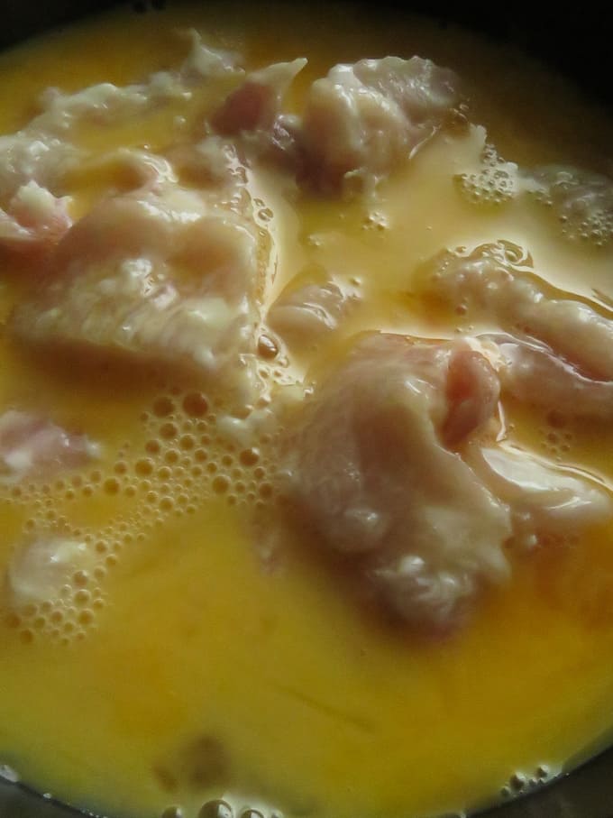 dipping chicken cubes in eggs and then coating with flour.