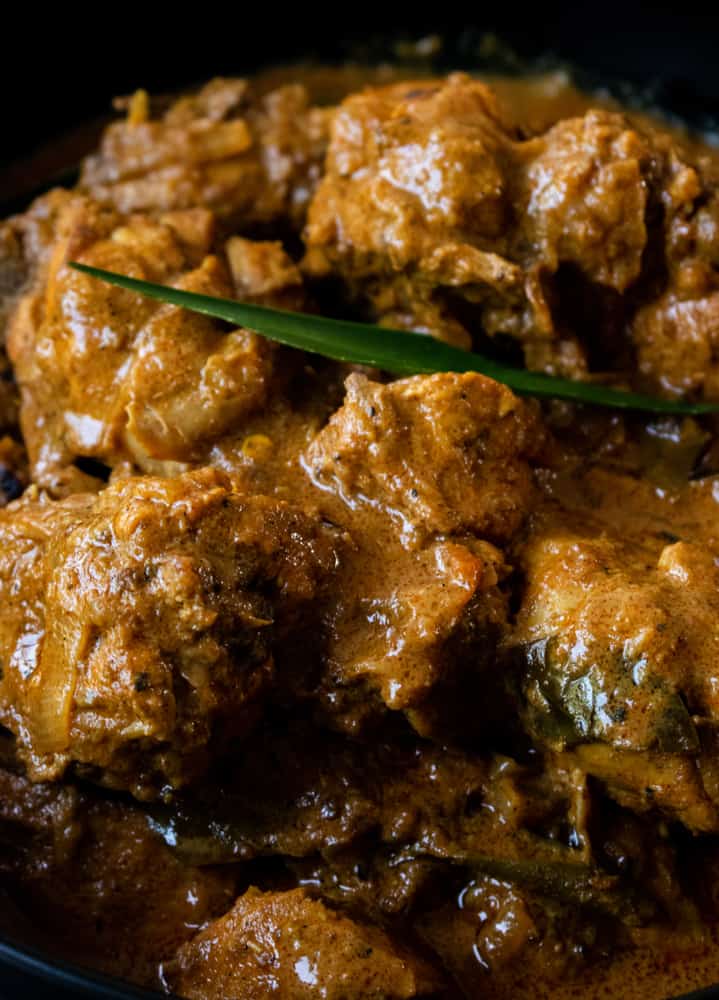 Sri Lankan chicken curry covered in thick spicy gravy placed in a black bowl.