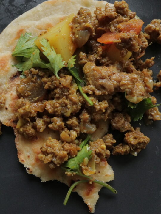 aloo keema on topped over a piece of naan roti,