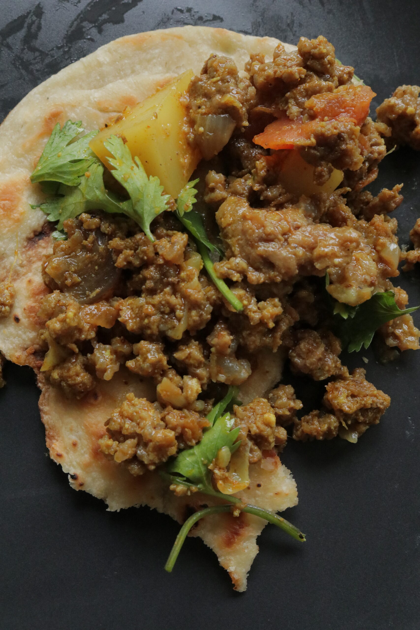 aloo keema on topped over a piece of naan roti,