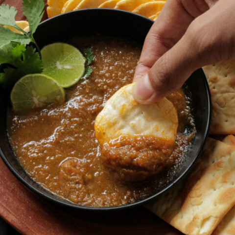 scooping tomato salsa with crackers.