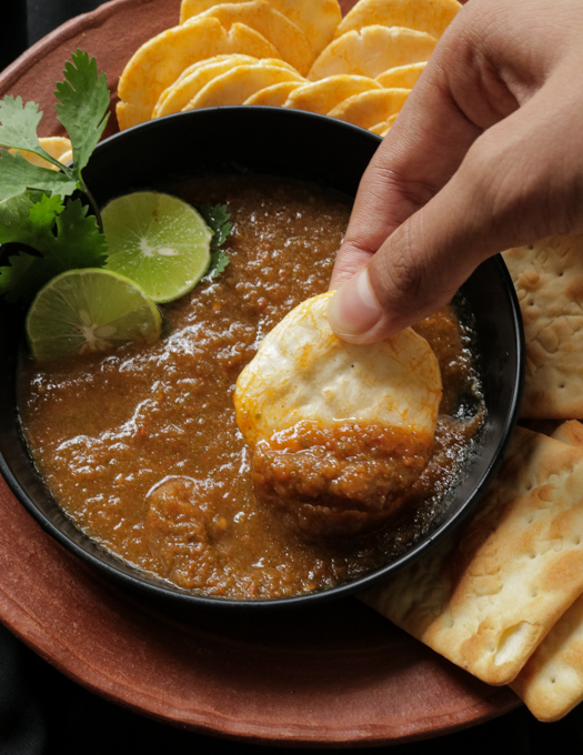 scooping tomato salsa with crackers.