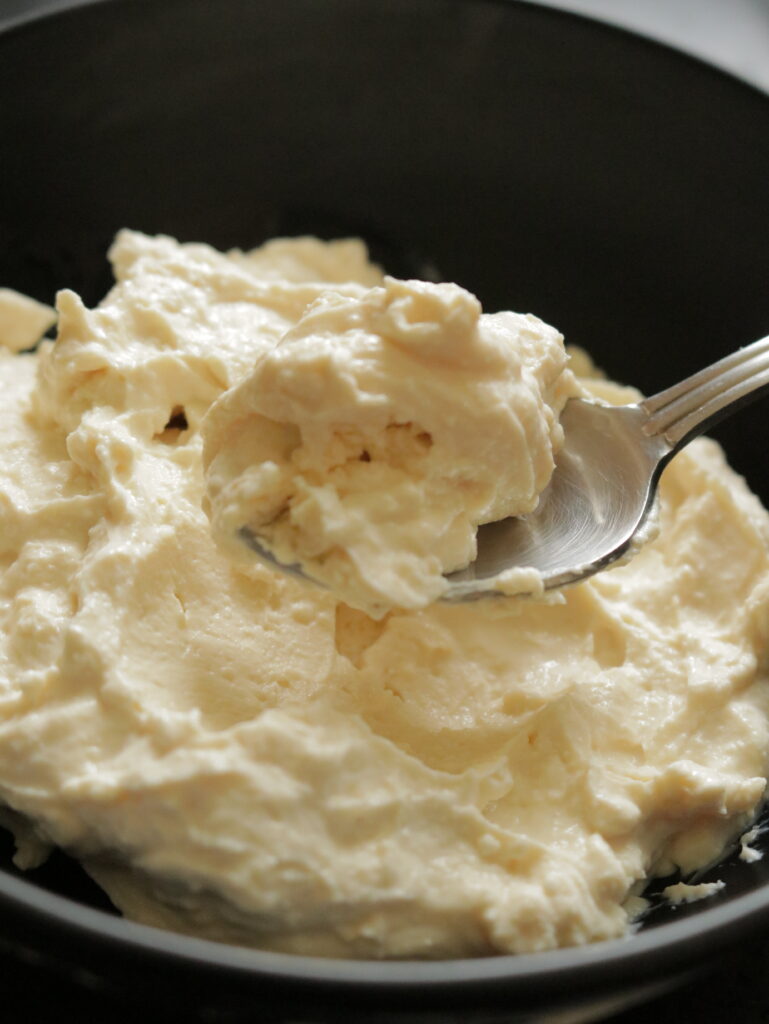 a bowl of cream cheese and a spoonful of cheese
